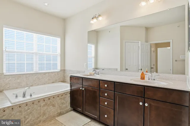 a bathroom with a tub sink double vanity granite and mirror