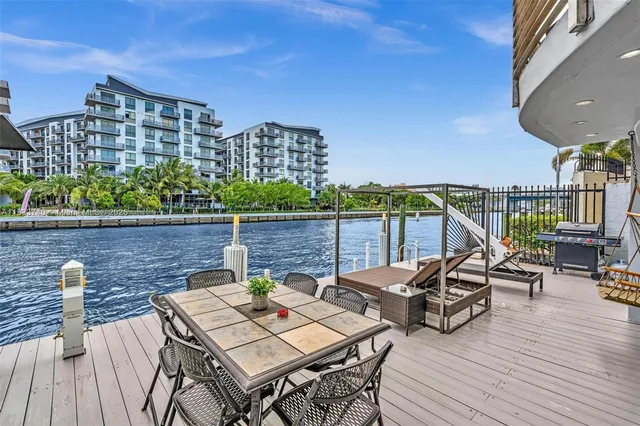 a view of a patio with couches table and chairs with wooden floor and fence