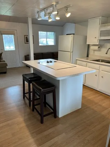 a kitchen with stainless steel appliances kitchen island a table chairs in it and a wooden floors