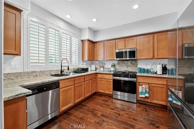 a kitchen with stainless steel appliances granite countertop wooden cabinets a sink and a stove