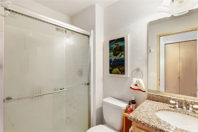 a bathroom with a granite countertop sink mirror vanity and toilet