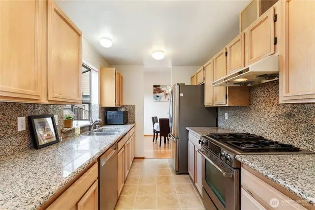 a kitchen with stainless steel appliances granite countertop a sink a stove and a refrigerator