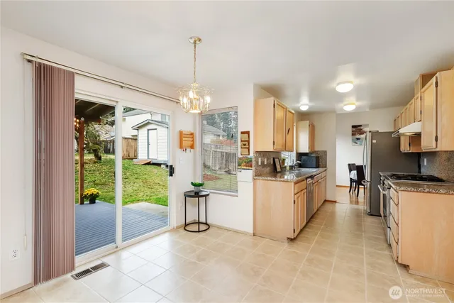 a kitchen with stainless steel appliances granite countertop a stove top oven a sink a refrigerator and a dining table