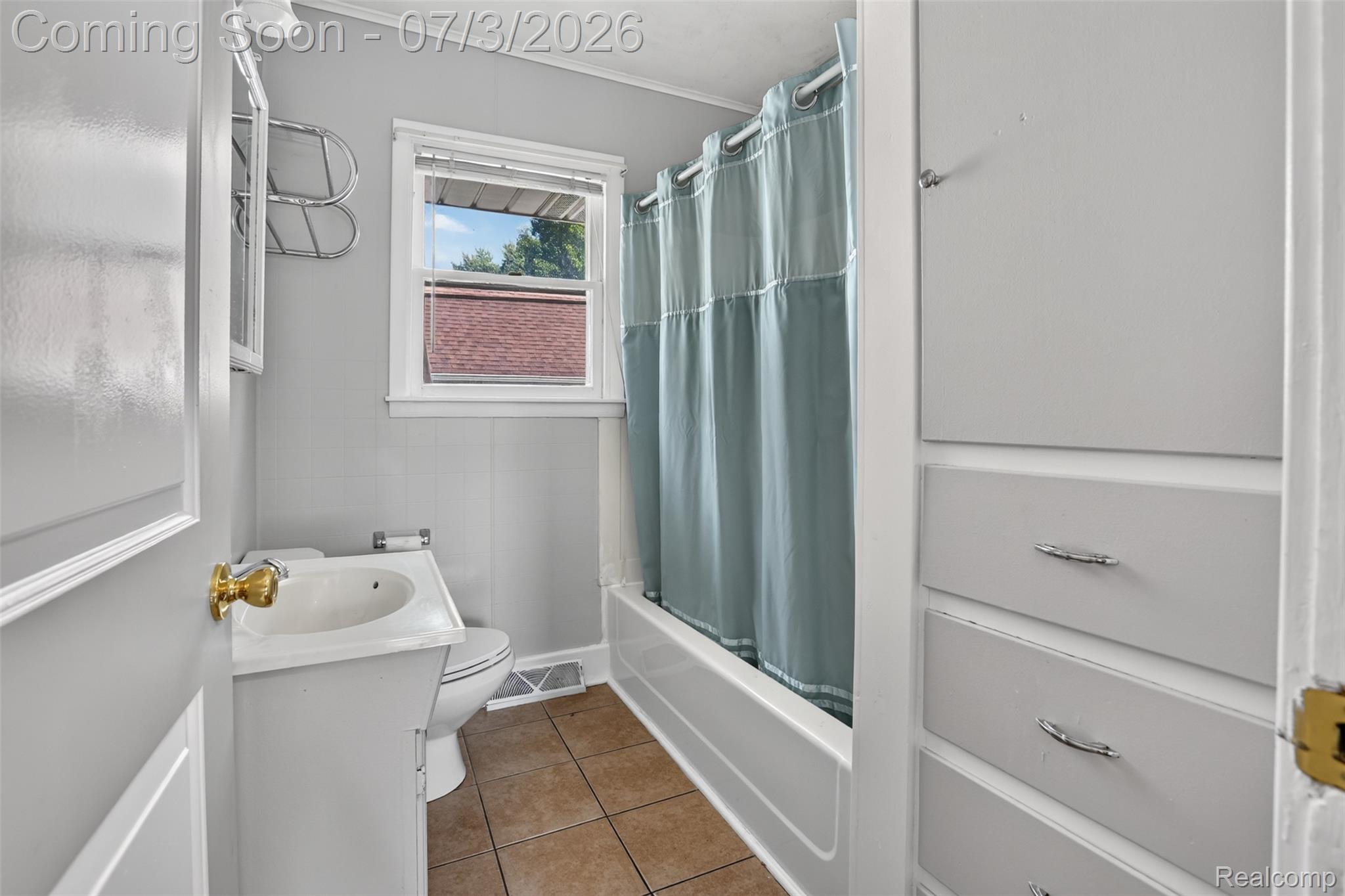 4322 Baker Road Bridgeport, MI 48722 - Photo 14 of 29 Bathroom featuring a single window, built-in storage cabinetry, vanity with integrated sink, a full bathtub, and tiled flooring
