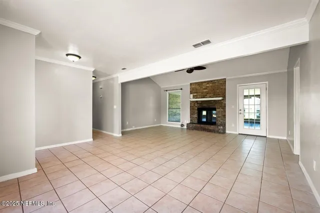 a view of an empty room and window with a chandelier fan