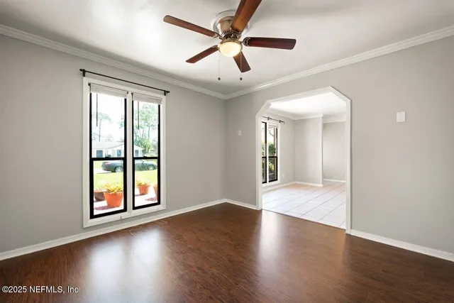 a view of an empty room with window and wooden floor