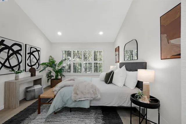a bedroom with a bed and potted plant next to a large window