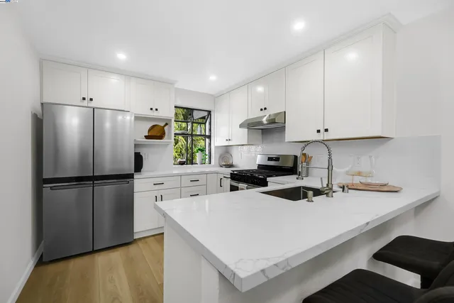 a kitchen with a appliances a sink a refrigerator and white cabinets