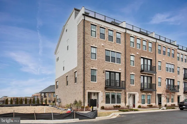 a front view of a building with lot of cars and trees