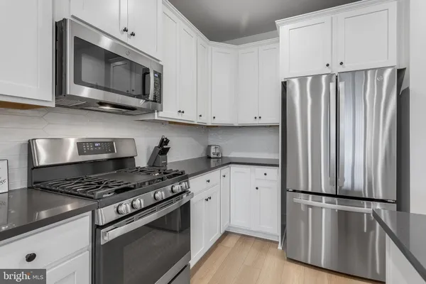 a kitchen with cabinets stainless steel appliances and wooden floor