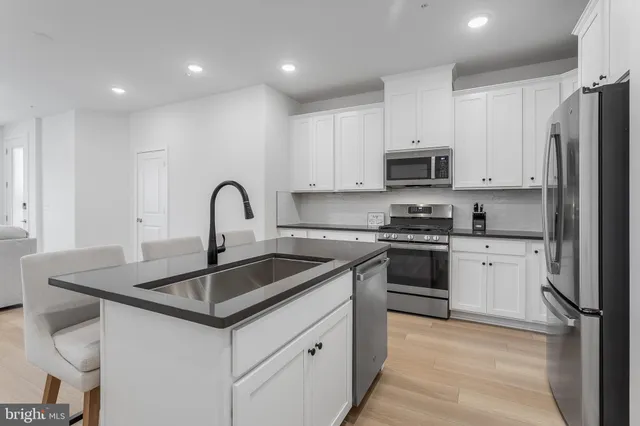 a kitchen with granite countertop a sink stainless steel appliances and white cabinets
