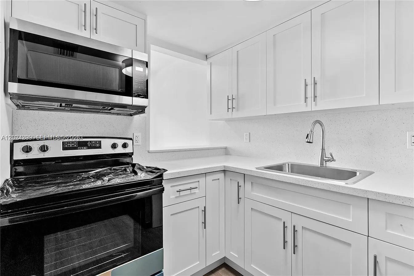 1351 Southwest 4th Street, Unit 8 Miami, FL 33135 - Photo 3 of 11 a kitchen with white cabinets and stainless steel appliances