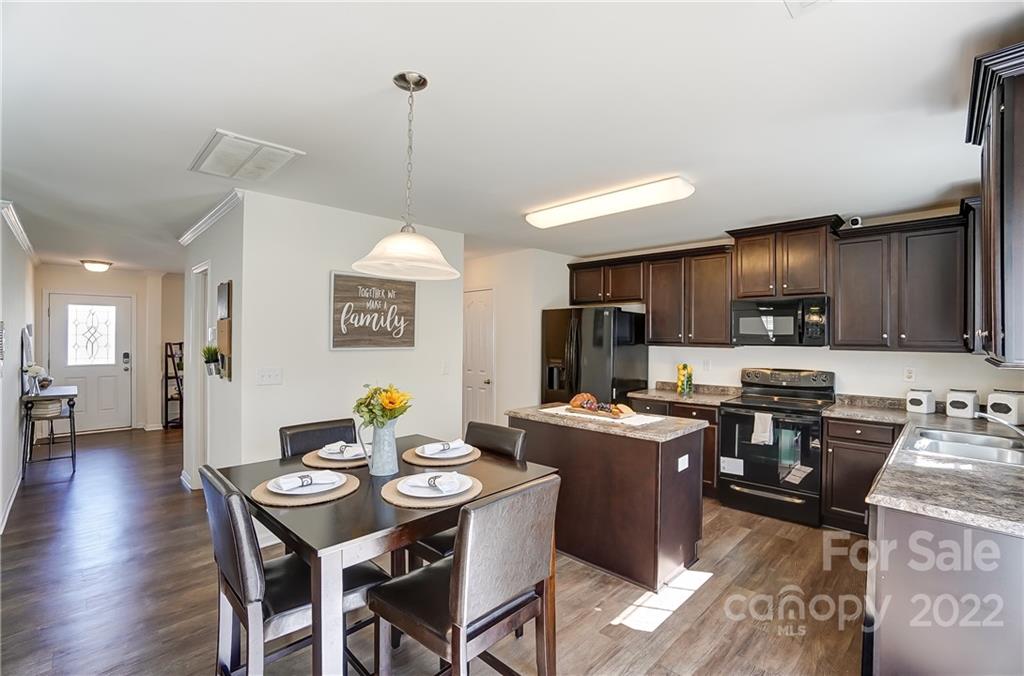 4715 McClure Road Charlotte, NC 28216 - Photo 7 of 36 a kitchen with stainless steel appliances granite countertop a stove a refrigerator a kitchen island a dining table and chairs with wooden floor