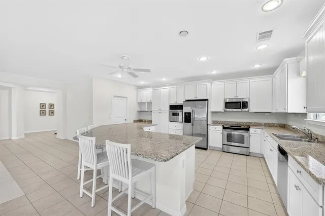 a kitchen with stainless steel appliances granite countertop a stove top oven a sink dishwasher and a refrigerator with wooden floor