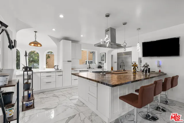 a kitchen with sink stove and white cabinets with wooden floor
