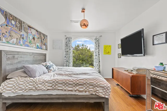 a bedroom with a bed and a flat tv screen on the dresser
