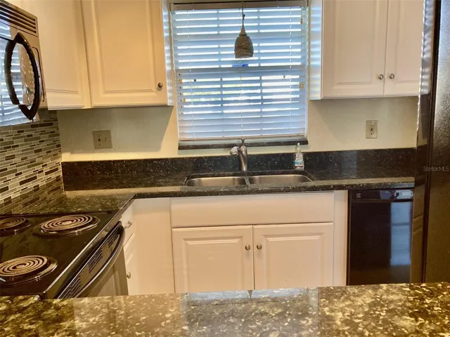 a kitchen with granite countertop a sink and a stove