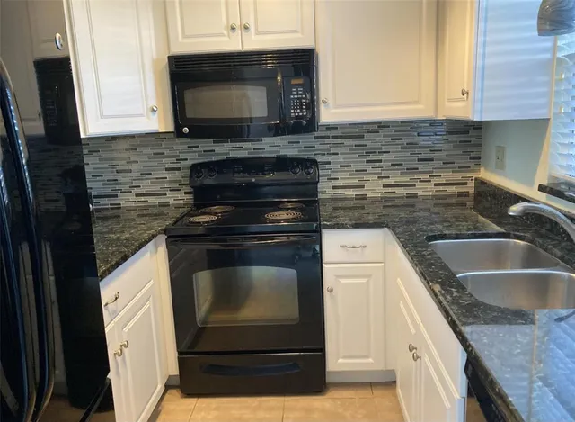 a kitchen with granite countertop a sink stove and microwave