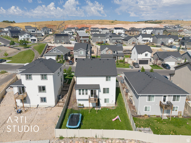 1713 South Windemere Road Santaquin, UT 84655 - Photo 38 of 40 Rear exterior of a two-story residence featuring a private fenced yard with green lawn, a ground-level deck, and a second-story balcony