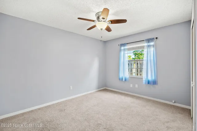 an empty room with window and ceiling fan