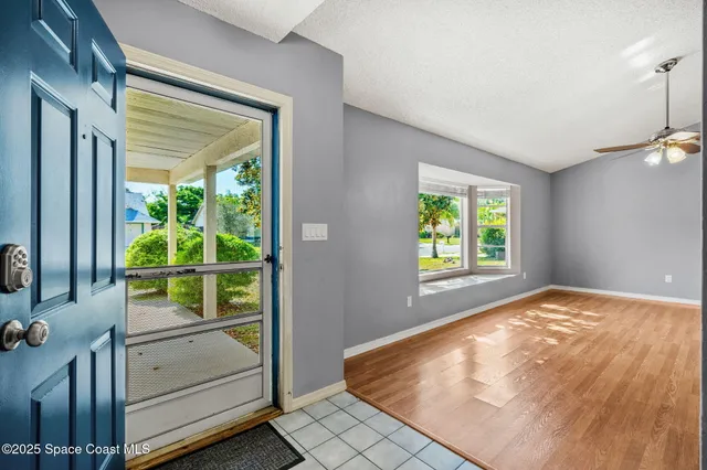 a view of an empty room with wooden floor and windows