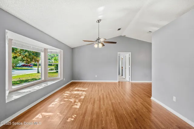 a view of empty room with wooden floor and fan