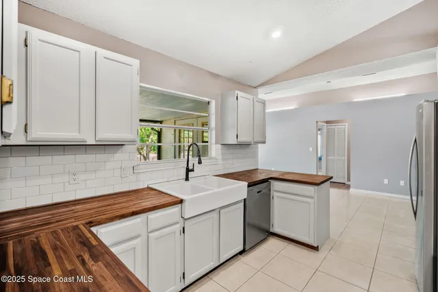 a kitchen with granite countertop a sink stainless steel appliances white cabinets and a window