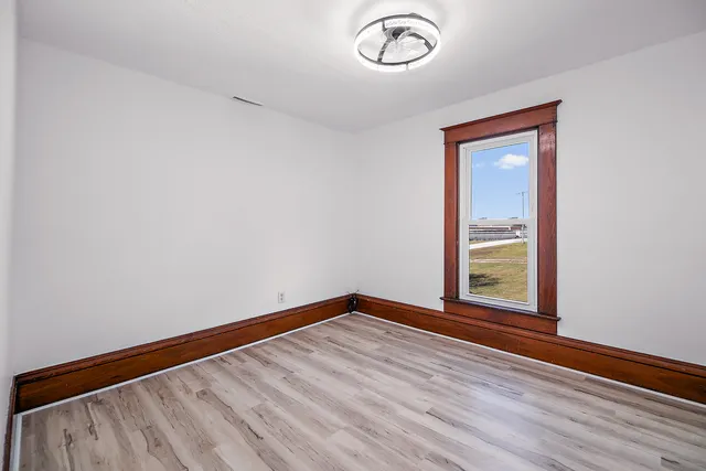 a view of an empty room with a window and wooden floor