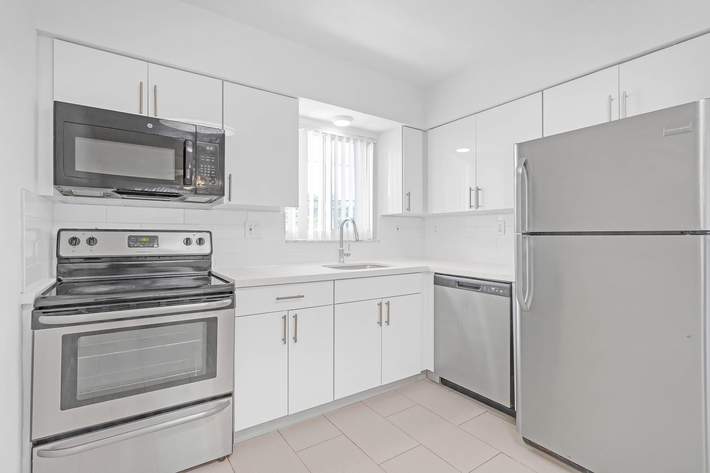330 West Camino Real Boca Raton, FL 33432 - Photo 11 of 18 a kitchen with white cabinets and stainless steel appliances
