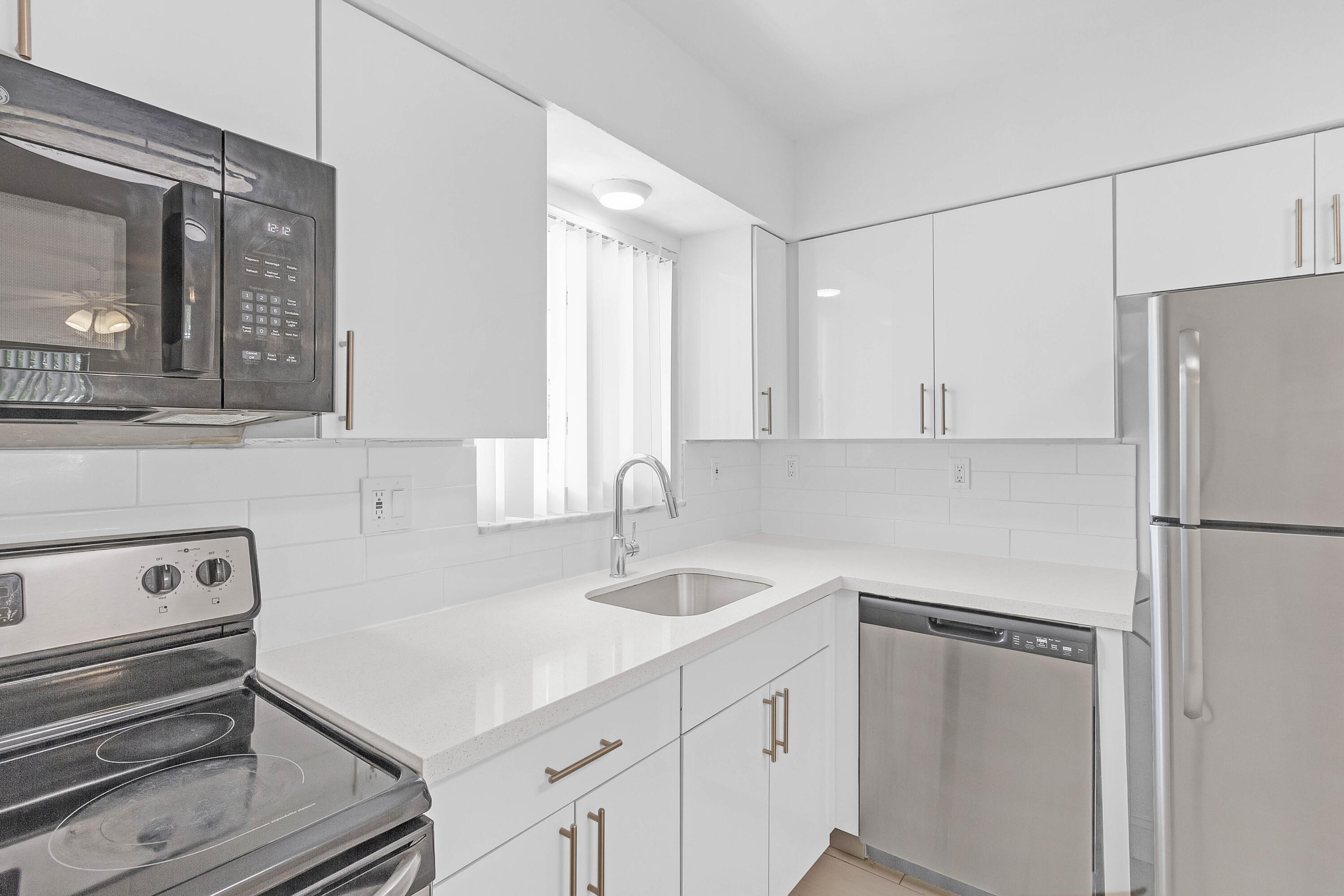 330 West Camino Real Boca Raton, FL 33432 - Photo 12 of 18 a white kitchen with cabinets appliances and a sink