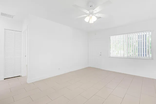 an empty room with a window and a ceiling fan
