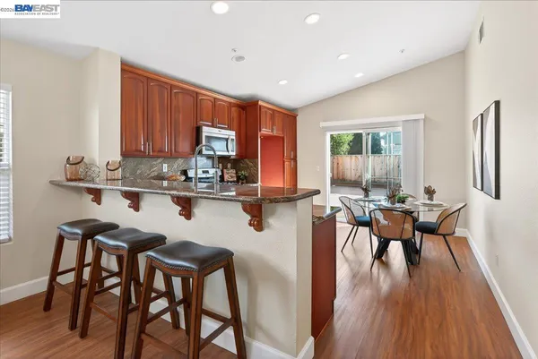 a kitchen with stainless steel appliances granite countertop table chairs stove and wooden floor