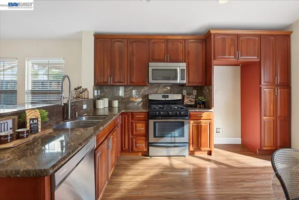 a kitchen with stainless steel appliances granite countertop a stove a sink dishwasher a refrigerator and a microwave oven with wooden cabinets