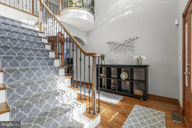 a view of a hallway to a livingroom with wooden floor and furniture