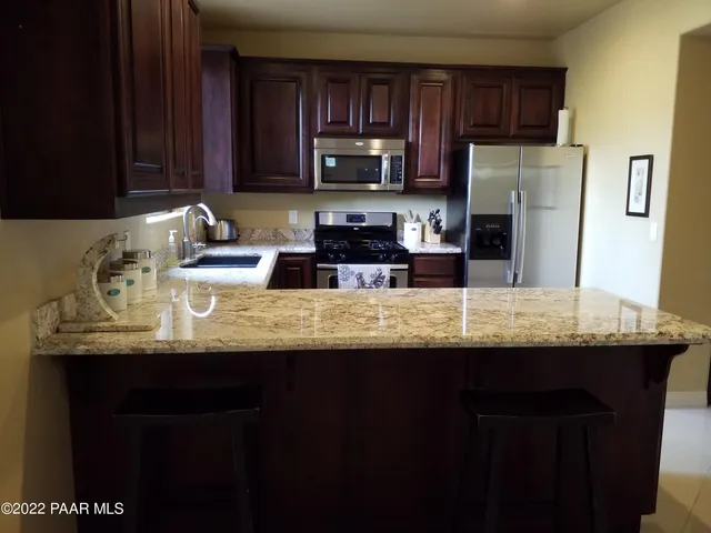 a kitchen with granite countertop a sink stainless steel appliances and cabinets