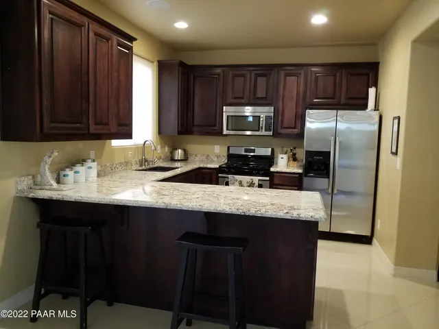 a kitchen with granite countertop wooden cabinets a refrigerator and a sink