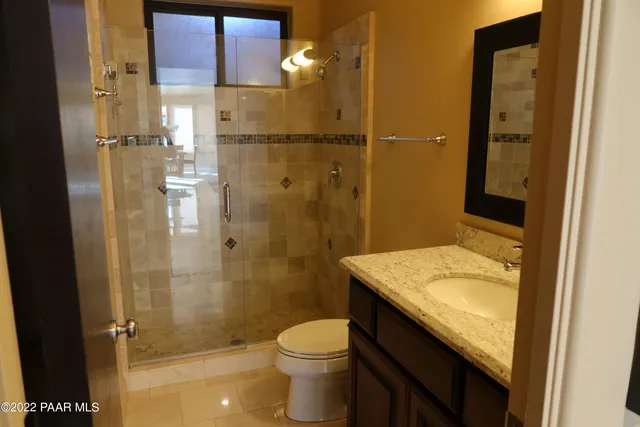 a bathroom with a granite countertop sink toilet and shower