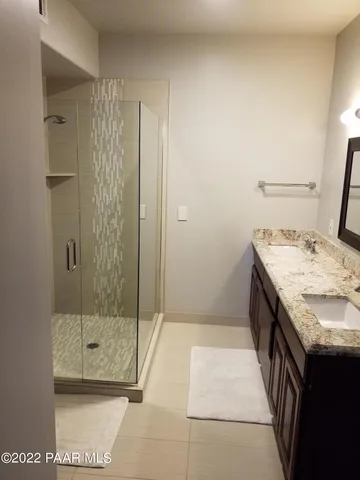 a bathroom with a granite countertop sink a mirror and shower