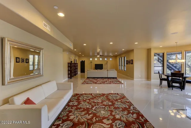 a large living room with stainless steel appliances furniture a rug and a view of kitchen
