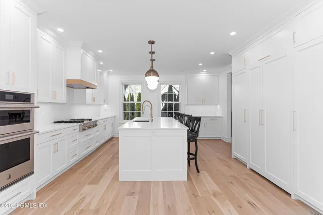 a kitchen with stainless steel appliances granite countertop a stove top oven a sink dishwasher and a refrigerator with wooden floor