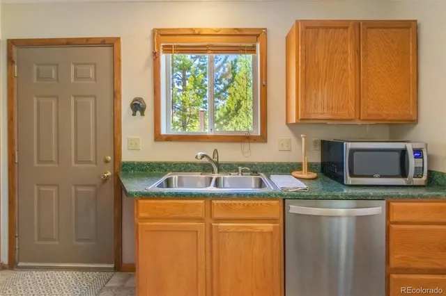 a kitchen with granite countertop cabinets stainless steel appliances a sink and a window
