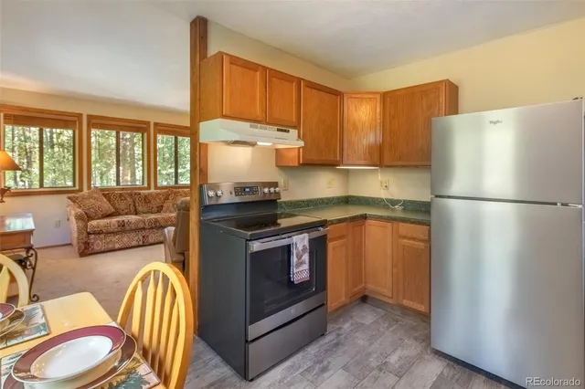 a kitchen with stainless steel appliances granite countertop a refrigerator a stove a sink and a more cabinets