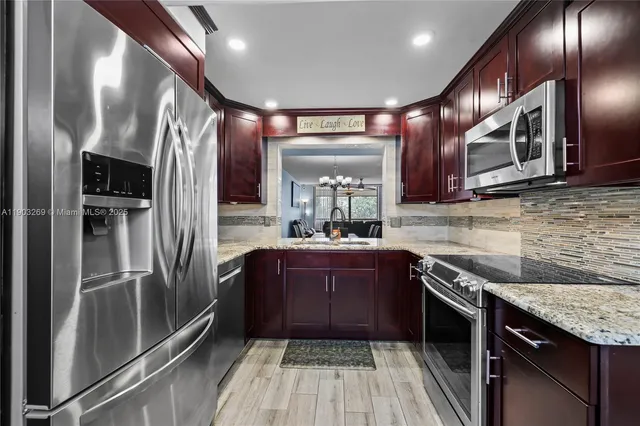 a kitchen with stainless steel appliances granite countertop a refrigerator a sink and wooden cabinets