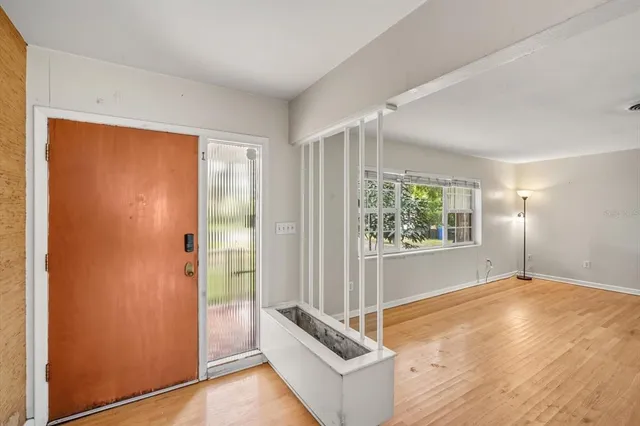 a view of an empty room with wooden floor and a window