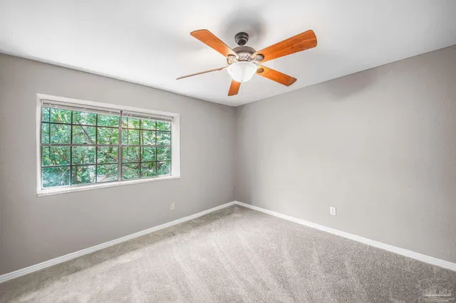 an empty room with ceiling fan and window
