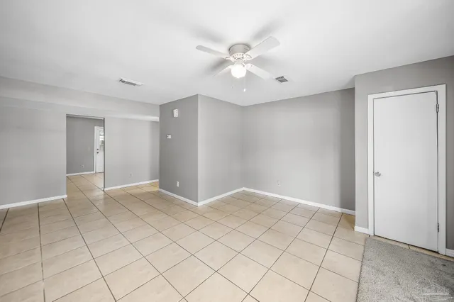 a view of an empty room and chandelier fan