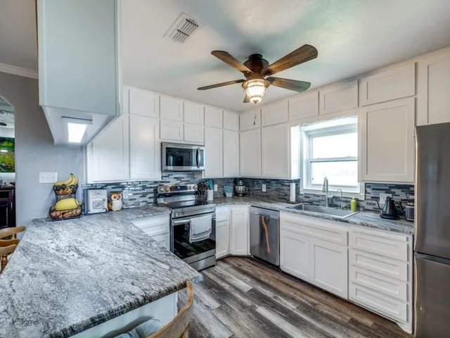 a kitchen with stainless steel appliances granite countertop a sink a stove and cabinets