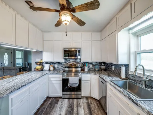 a kitchen with granite countertop a sink stainless steel appliances and cabinets
