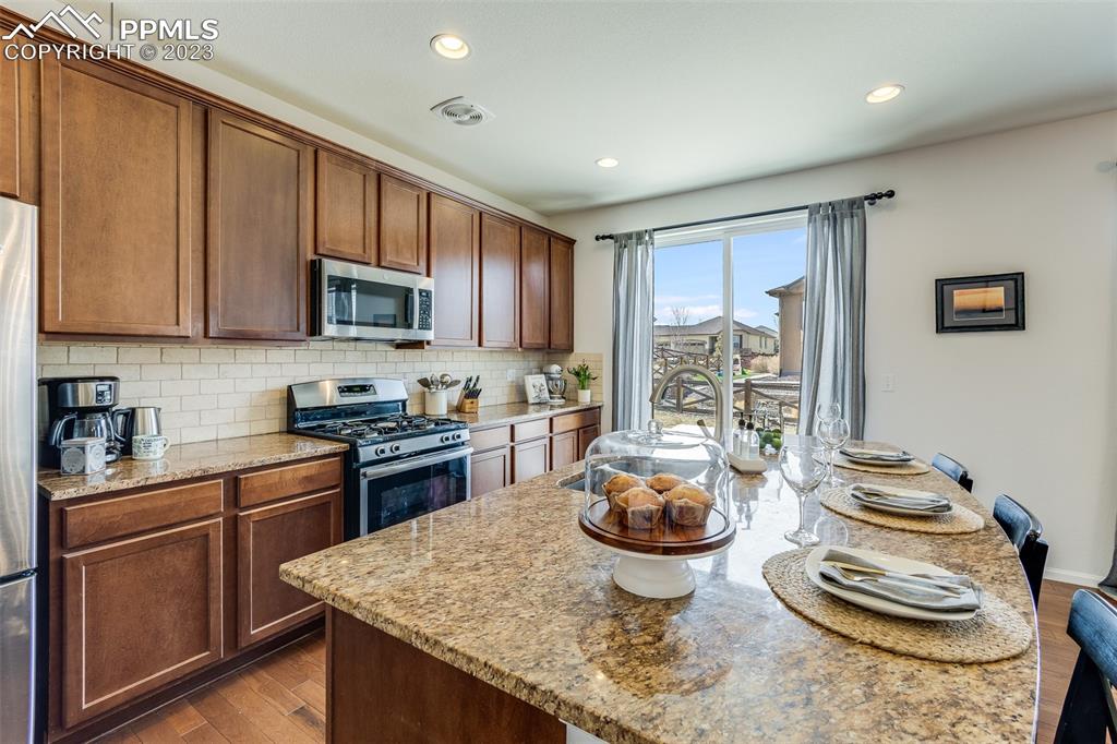 7122 Golden Acacia Lane Colorado Springs, CO 80927 - Photo 10 of 37 a kitchen with stainless steel appliances granite countertop a stove top oven a sink and cabinets