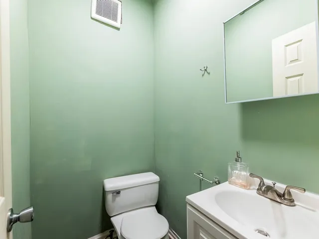 a white toilet sitting next to a white sink and vanity